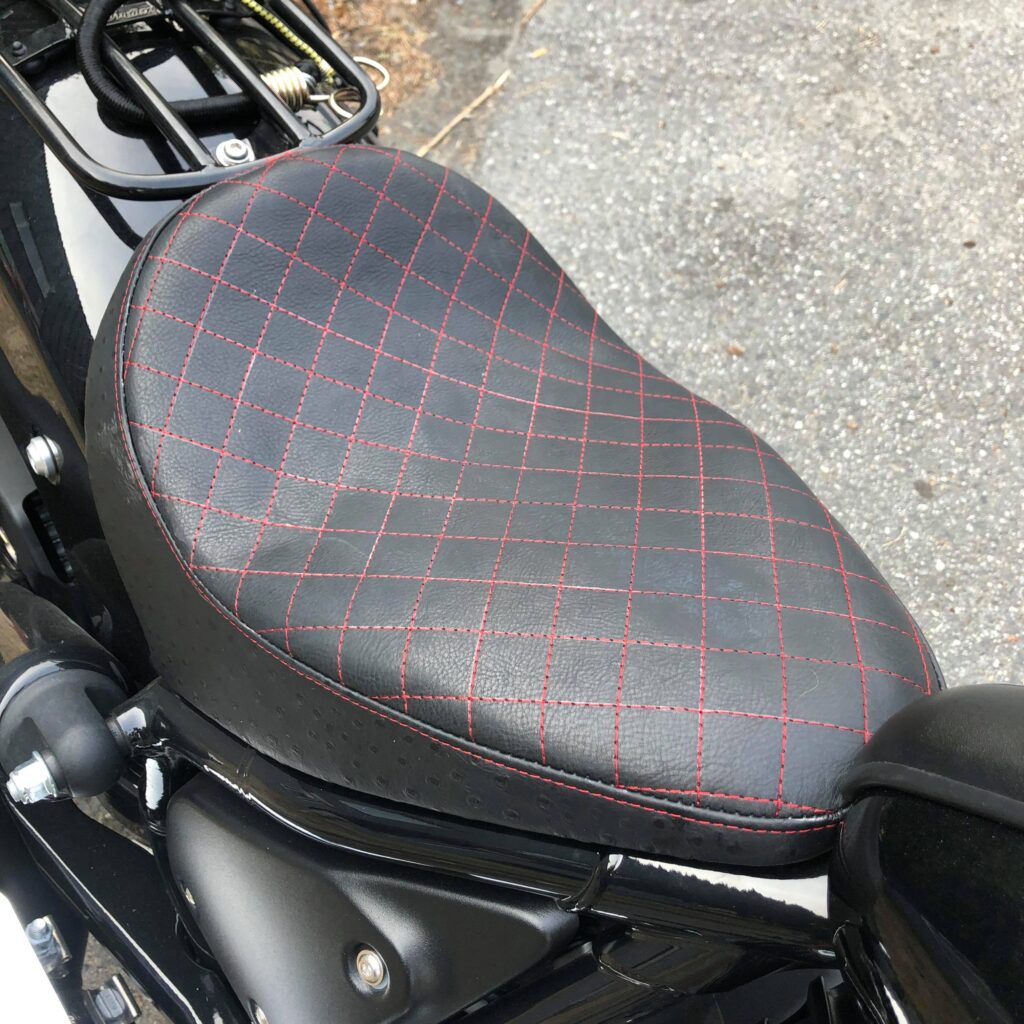 An upholstery motorcycle seat featuring red diamond stitching