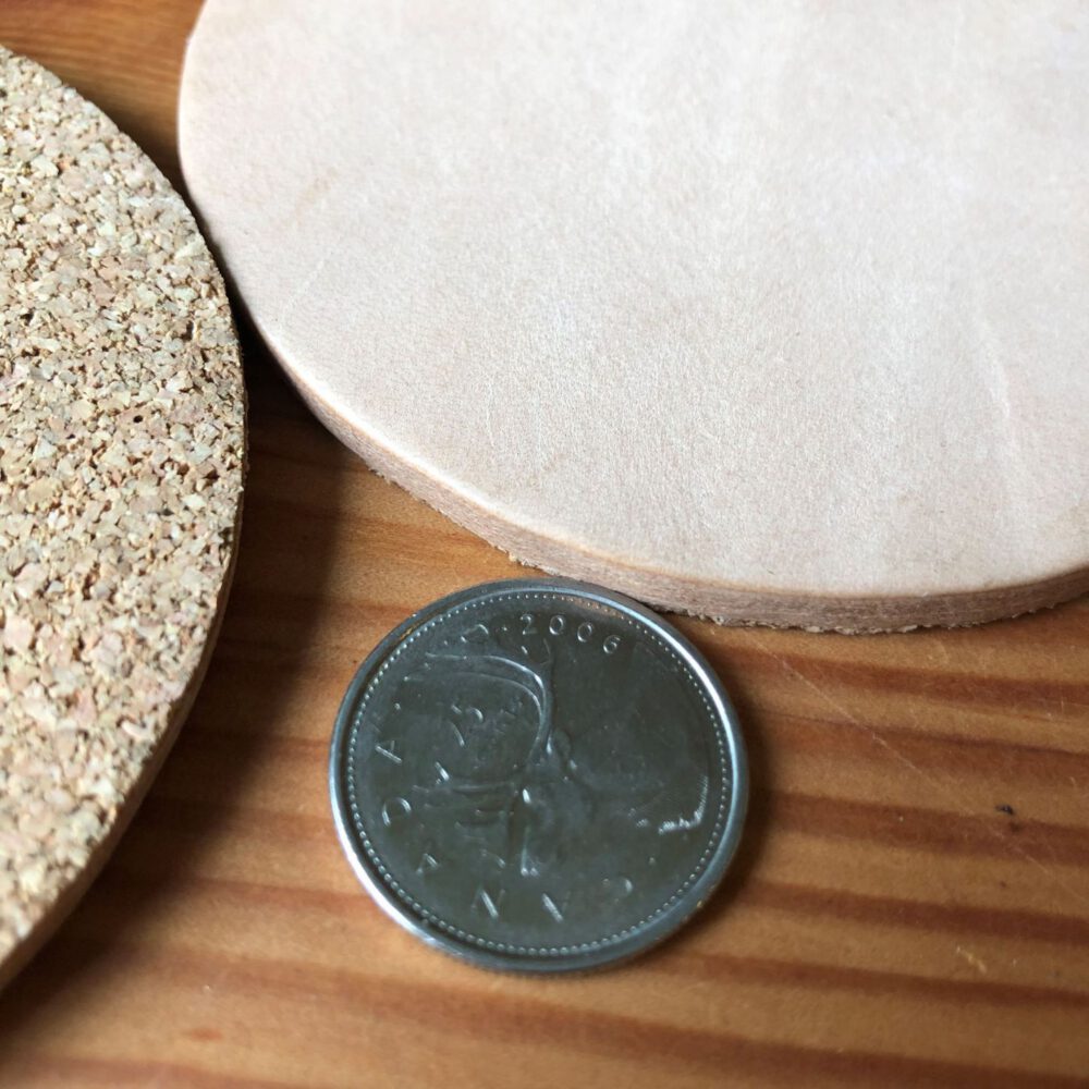 A quarter beside a leather coaster