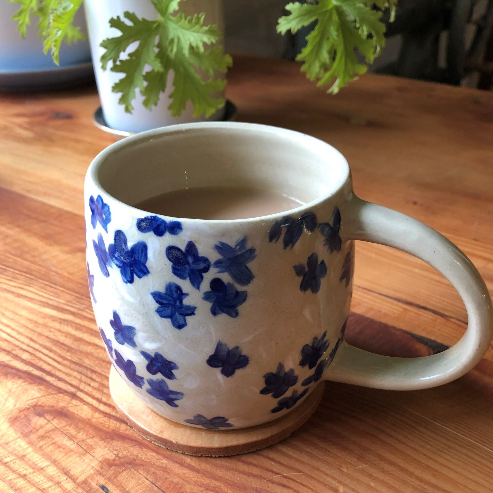 A blue floral mug sitting on a leather coaster