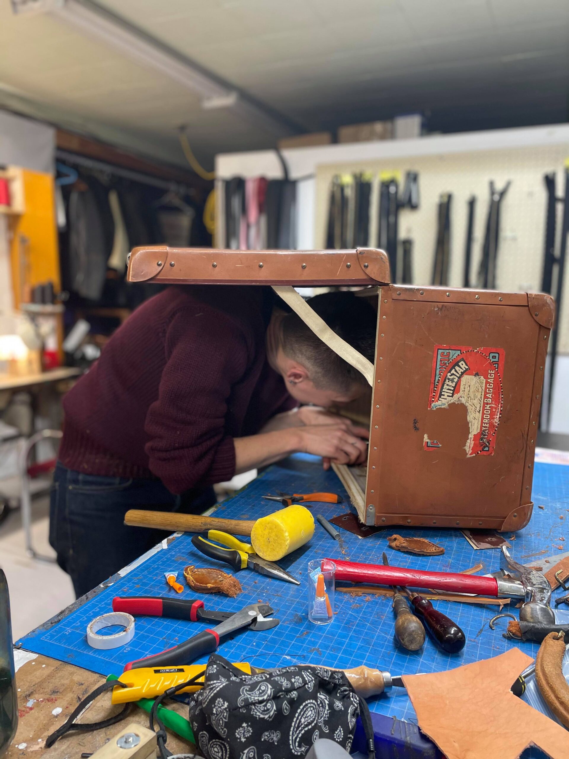 Ariss performing a bag restoration, by having their head inside a vintage suitcase